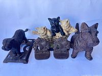 Front view of all cast iron pieces: cat doorstop, ship bookends pair, Scottie figure, black dog figure