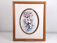 Frontal image of the framed 3D paper tole art showing flowers and butterfly in pastel colors with wooden frame and glass cover.