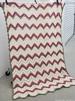 Full view of rectangular crocheted tablecloth draped vertically showing entire chevron pattern and scalloped edges.