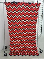 Full view of the crocheted chevron pattern tablecloth hanging vertically, showing the complete rectangular item and its pattern.