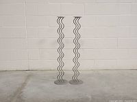 Full front view of both grey metal candle holders against a white brick wall