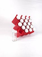 Red vintage Copco spice rack holding 18 clear glass spice bottles with white lids, viewed from an angle showing three rows and spacing between bottles.