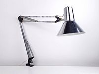 Side view of the articulated chrome lamp fully extended horizontally with clamp base attached to desk edge.