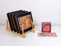 Four cat-themed vintage table mats standing in a wooden holder, next to a small box and two visible Scrabble-themed coasters.