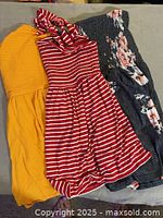 all three garments laid flat: mustard romper, red striped dress, grey floral dress
