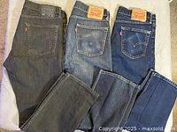 Three pairs jeans laid flat showing back pockets and colors