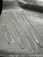 Four silver-tone chain necklaces laid out to show styles and lengths