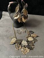 Full set showing necklace, large dangle earrings on stand, small earrings on surface