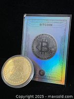 Front of holographic Bitcoin trading card beside gold-tone coin