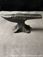 Left side view of cast iron anvil showing raised JOHN DEERE lettering and patina