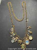 Full view of gold-tone charm necklace on dark background