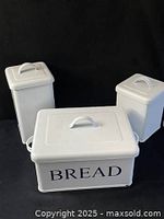 Front view of three white enamel containers with lids; bread box labeled "BREAD"