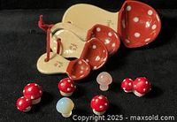 Nested ceramic mushroom measuring spoons and seven mini mushroom figurines on black background