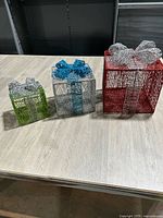Three wire mesh gift boxes in varying sizes and colors