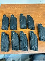 Top view of nine black Safariland basketweave holsters arranged on table