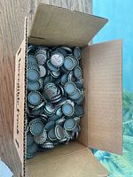 Open box showing large quantity of unused Coca-Cola bottle caps