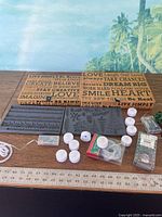 overview of all items laid out: two wooden/cork boxes, two grey silicone molds, white LED tealights, cord, thread spool, small organizer, embellishment pack