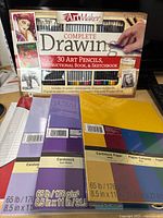 Front of ArtMaker Complete Drawing set box alongside three cardstock packs