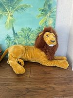 Full view of lion plush lying on wooden surface