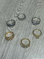 All six rings laid out showing metal tones and stone settings