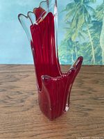Front view of red glass vase showing clear tipped rim and flared form
