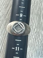 Front view of sterling silver signet ring on mandrel showing design and size markers