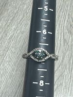 Front view of sterling silver ring on mandrel showing green stone cluster and CZ accents