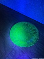 Plate glowing under UV light showing etched pattern