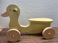 Full side view of wooden ride-on duck on four wheels