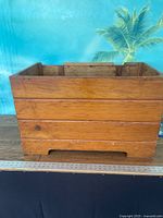 Front view of wooden storage box showing tongue-and-groove panels and cut-out feet