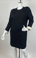 Full view of black dress on mannequin showing overall style, cuffs, buttons