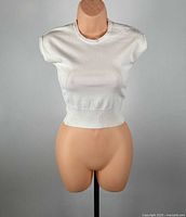 Front view of white knit top on mannequin showing overall design and fit