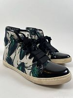 Side angle of sneakers showing beetle print, laces, patent toe
