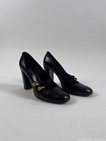 Three-quarter view of both shoes showing overall design, heel style, and gold hardware