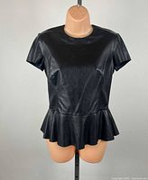 Front view of black leather peplum top on mannequin
