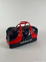 Front view showing Adidas logo, red handles, navy body