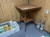 Full view of wood parlour table showing top, turned legs, lower shelf, and metal claw feet with glass balls
