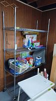 Full view of chrome wire shelving unit with four shelves and casters, contents excluded