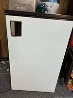 Front view of white vintage bar fridge showing recessed handle and brown trim