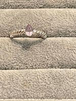 Front view of sterling silver ring with pear-cut amethyst on display pad