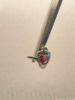 Front view showing falcon motif and pink-red stone