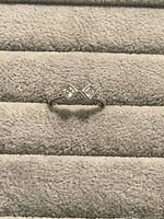 Ring on display pad showing bypass design, twin square stones, pave shoulders