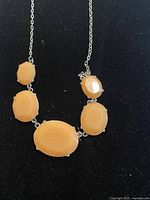 Front view of necklace showing all five peach cabochons on silver-tone chain