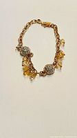 Full view of bracelet laid flat showing chain, pavé beads, yellow dangles, clasp
