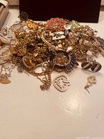 Pile of mixed gold-tone jewelry with chains, pendants, earrings