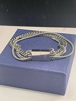 Bracelet coiled on blue box showing chain variety and clasp