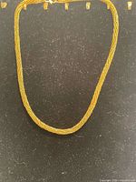 Full view of gold tone twisted chain necklace laid flat