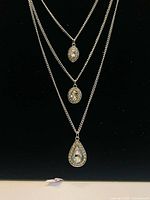 Full view of triple-strand rhinestone necklace against black background