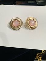 Front view of both earrings showing gold-tone sunburst design and pink centres