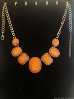 Front view of entire necklace on black display showing chain and five cabochons